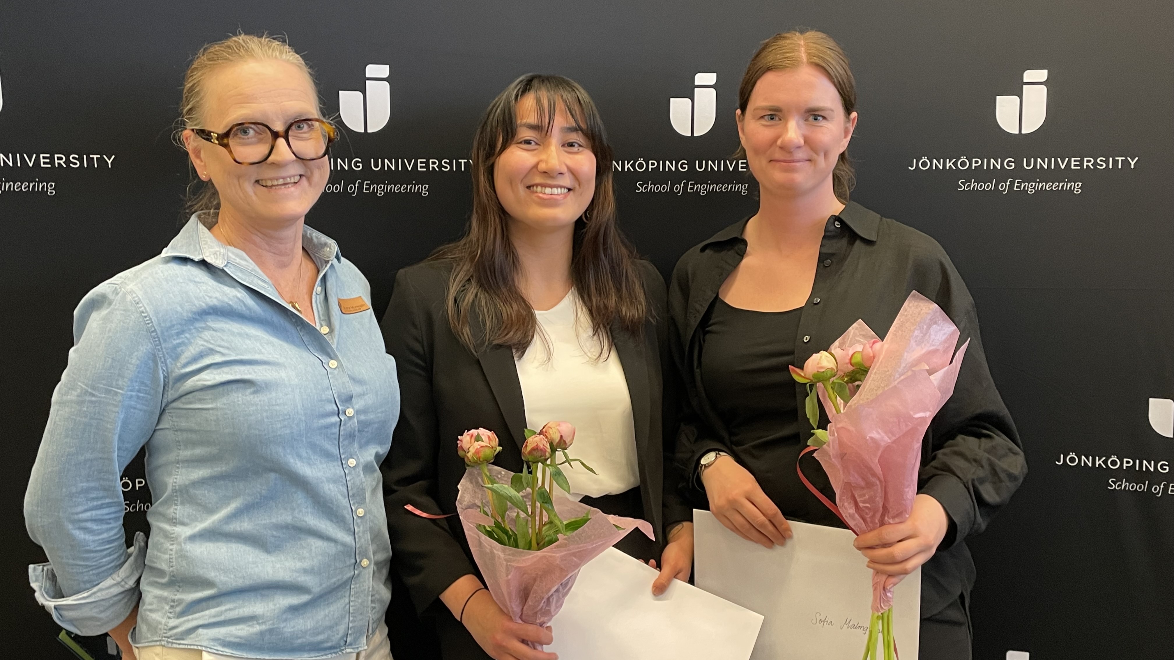 Bild på 3 kvinnor. Två av dem håller i blommor och diplom
