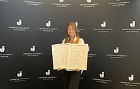 En av stipendiaterna syns på bilden med diplom och mot en bakgrund med Jönköping Universitys logotype.
