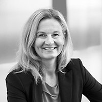 Blond kvinna tittar leende in i kameran.